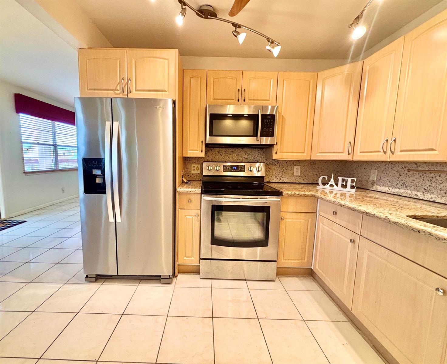 A kitchen features light wood cabinets, stainless steel appliances, and speckled granite countertops — 4032 Newcastle B, Boca Raton FL 33434, BOCA RATON, FL