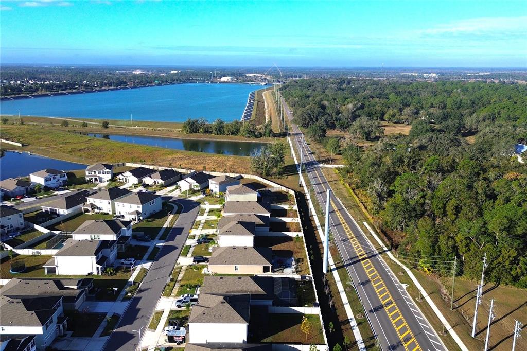 An aerial view shows a suburban neighborhood adjacent to a large reservoir and road — 8406 HARDY BAY LOOP, WESLEY CHAPEL, FL