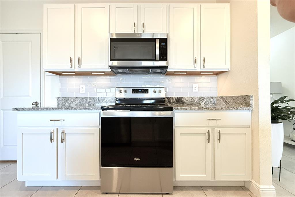 A kitchen features white cabinets, stainless steel appliances, and a granite countertop with tile backsplash — 8406 HARDY BAY LOOP, WESLEY CHAPEL, FL
