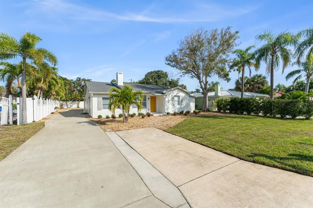 A single-story house with a concrete driveway, white siding, and palm trees under a blue sky — 107 4TH STREET, BELLEAIR BEACH, FL