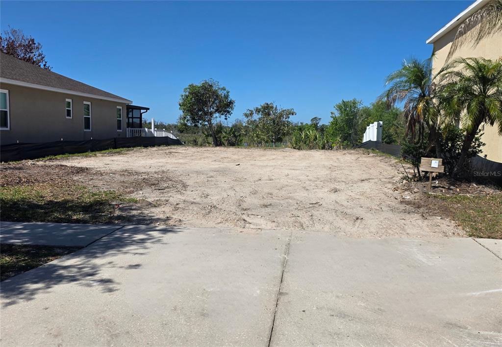 A vacant, cleared residential lot sits between two existing houses under a clear blue sky — 563 VISTA RIDGE DRIVE, RUSKIN, FL