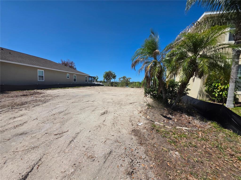 A vacant, sandy residential lot sits between two houses under a clear blue sky — 563 VISTA RIDGE DRIVE, RUSKIN, FL