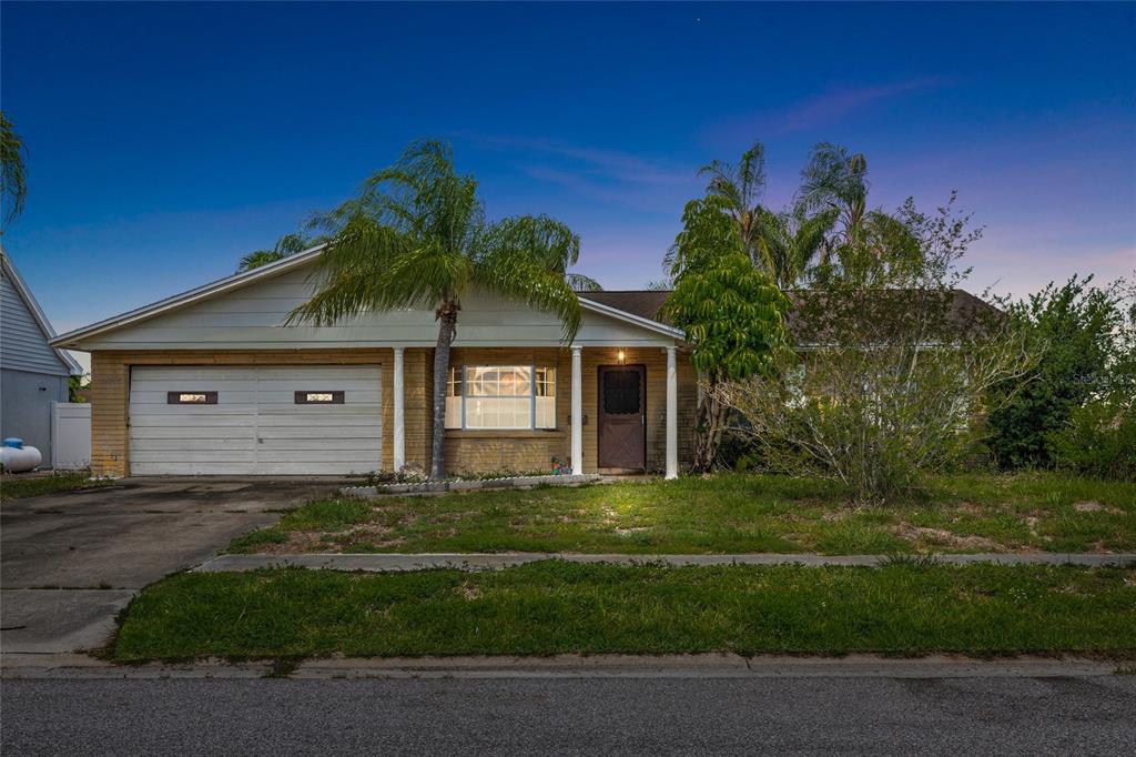 A single-story brick house with a two-car garage, front porch, and palm tree — 4709 TRAVERTINE DRIVE, TAMPA, FL
