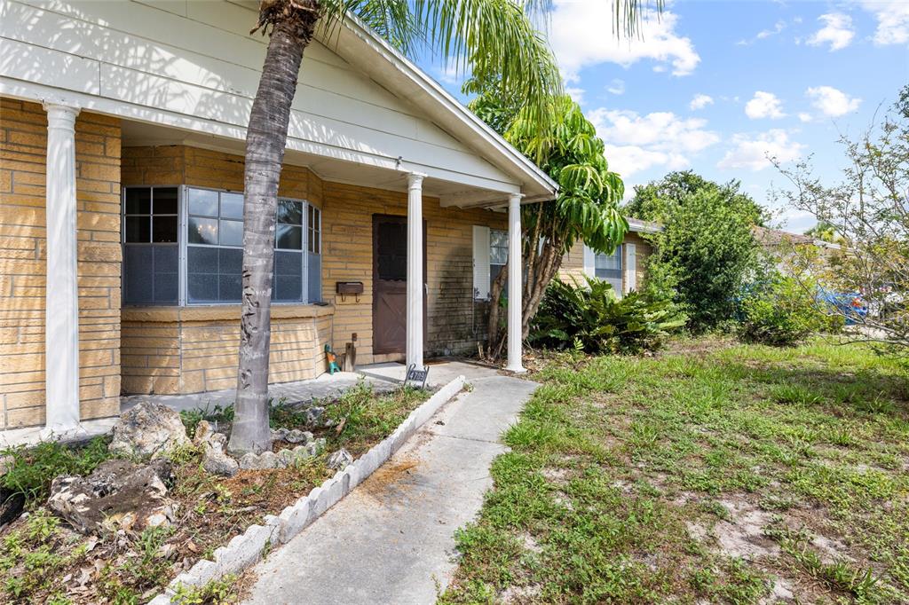 A single-story house with a brick facade, white columns, and a concrete walkway — 4709 TRAVERTINE DRIVE, TAMPA, FL