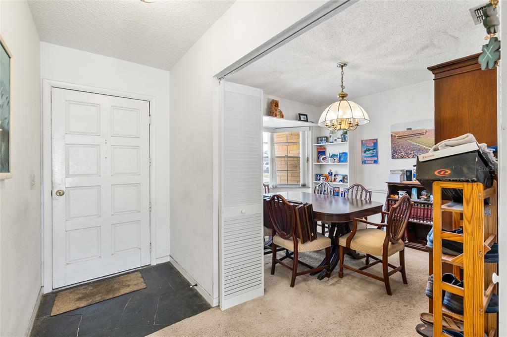 An entryway with a white door leads into a dining room featuring a wooden table — 4709 TRAVERTINE DRIVE, TAMPA, FL