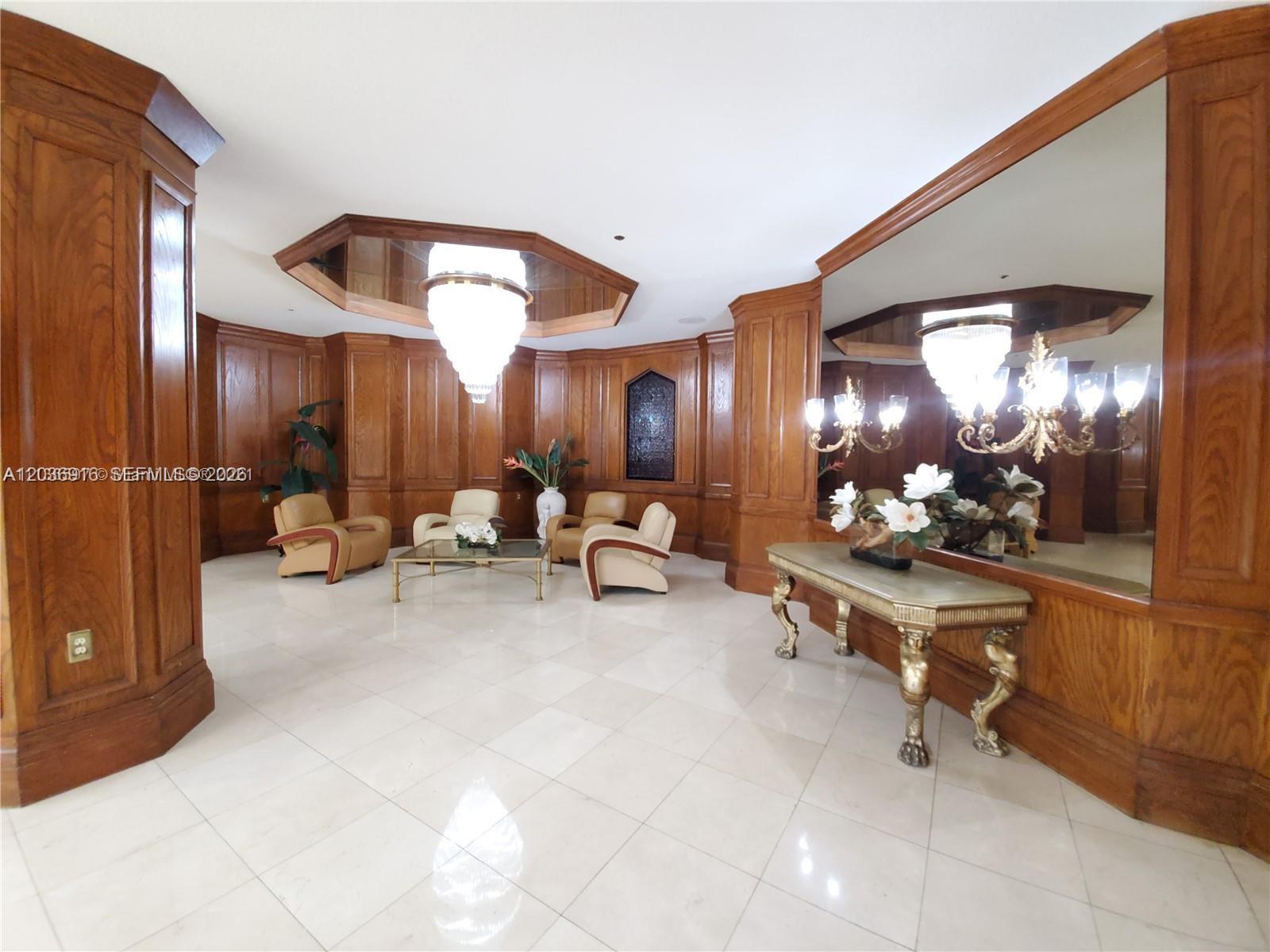 A formal lobby features wood-paneled walls, a large mirror, chandeliers, and light-colored tile flooring — 1865 S Ocean Dr # 11L, Hallandale Beach FL 33009, HALLANDALE BEACH, FL