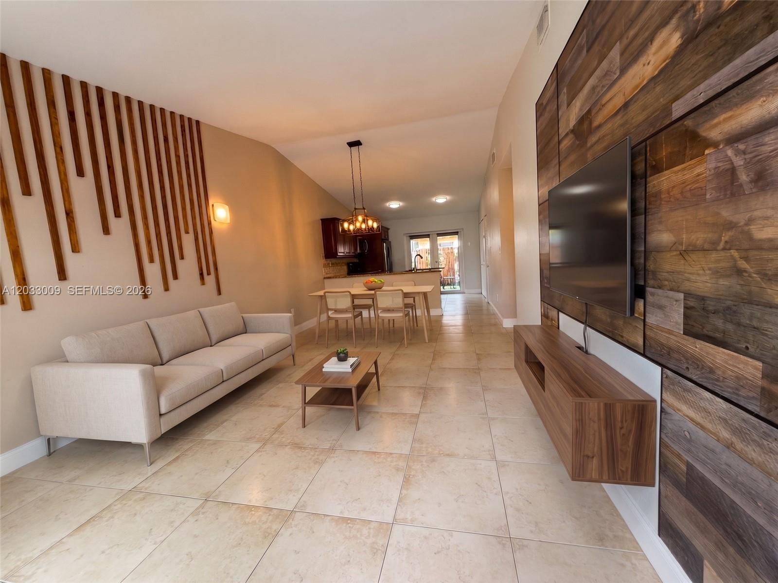 A living room features a wood-paneled accent wall, a sofa, and a dining area beyond — 7675 NW 181st St # 7675, Hialeah FL 33015, HIALEAH, FL