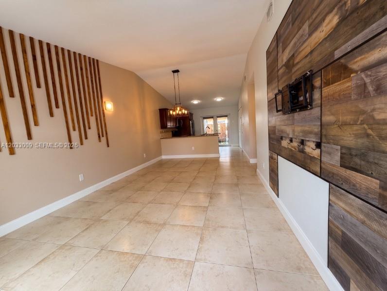 A living area with tile floors, a wood-slat wall feature, and a wood-paneled accent wall — 7675 NW 181st St # 7675, Hialeah FL 33015, HIALEAH, FL