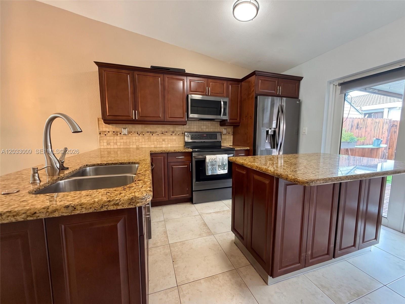 A kitchen features dark wood cabinets, granite countertops, stainless steel appliances, and tile flooring — 7675 NW 181st St # 7675, Hialeah FL 33015, HIALEAH, FL