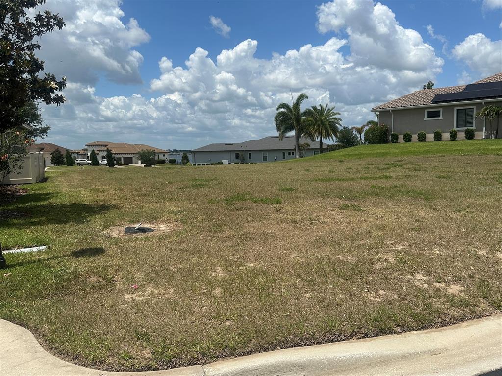 A vacant, grassy residential lot sits in front of neighboring houses under a cloudy sky — 126 STARGRASS DRIVE, AUBURNDALE, FL