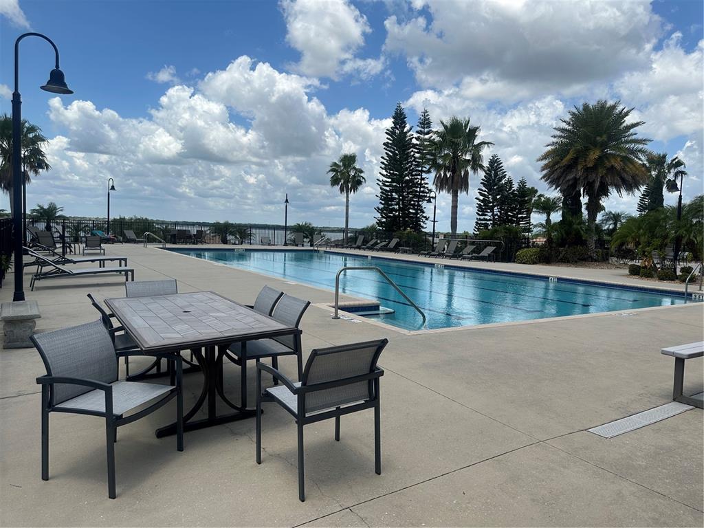 An outdoor swimming pool area features a dining set, lounge chairs, and palm trees — 126 STARGRASS DRIVE, AUBURNDALE, FL