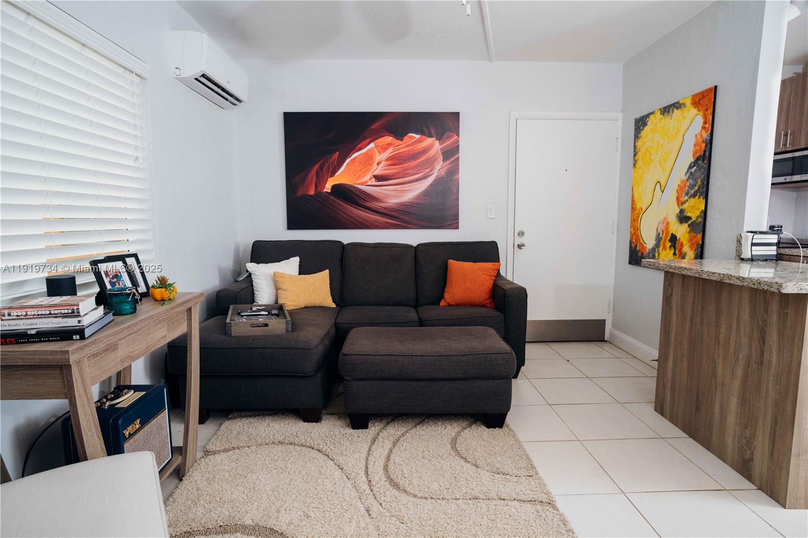 A living room features a dark gray sectional sofa, a beige area rug, and wall art — 7901 SW 64th Ave # 6, South Miami FL 33143, SOUTH MIAMI, FL
