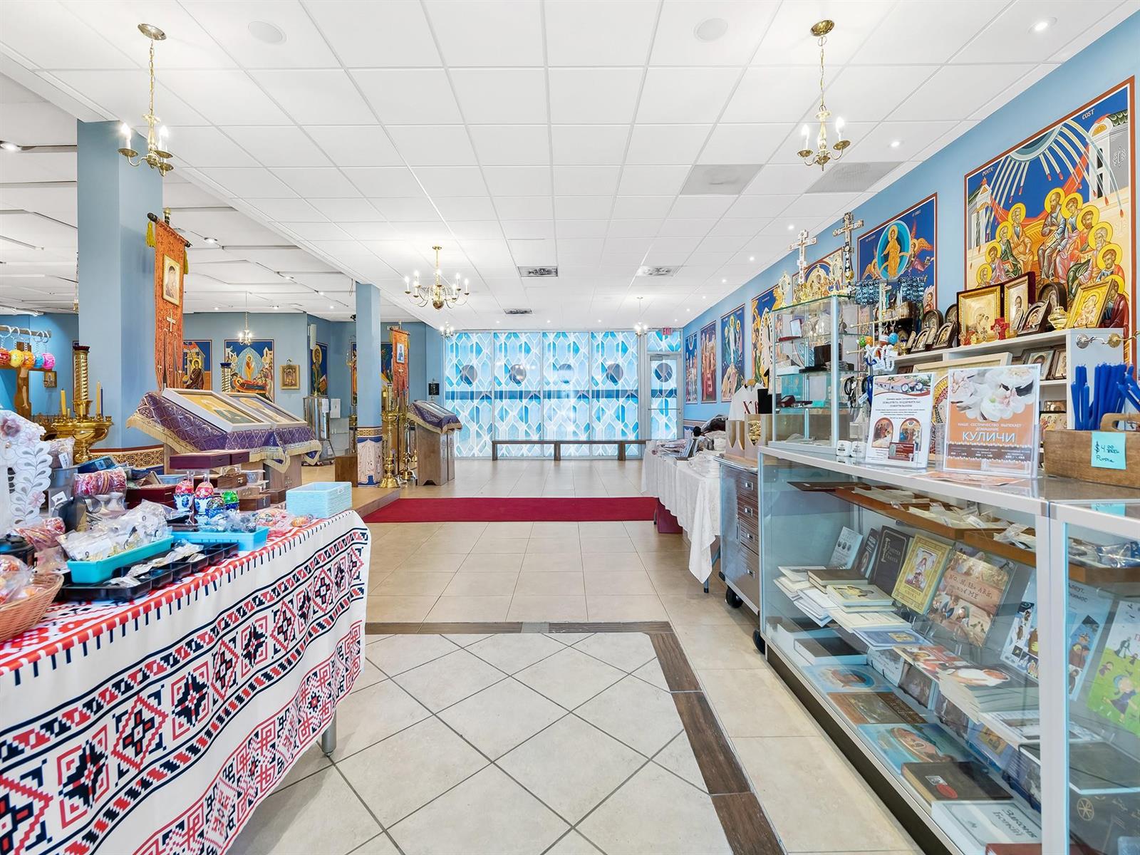A retail space featuring religious icons, books, and traditional textiles displayed on tables and shelves — 1301 E Atlantic Boulevard Suite 5, Pompano Beach FL 33060, POMPANO BEACH, FL