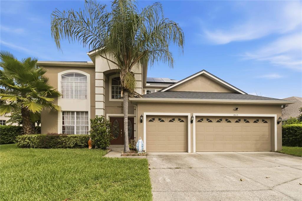 A two-story house with a beige exterior, a palm tree, and a three-car garage — 1845 OAK GROVE CHASE DRIVE, ORLANDO, FL