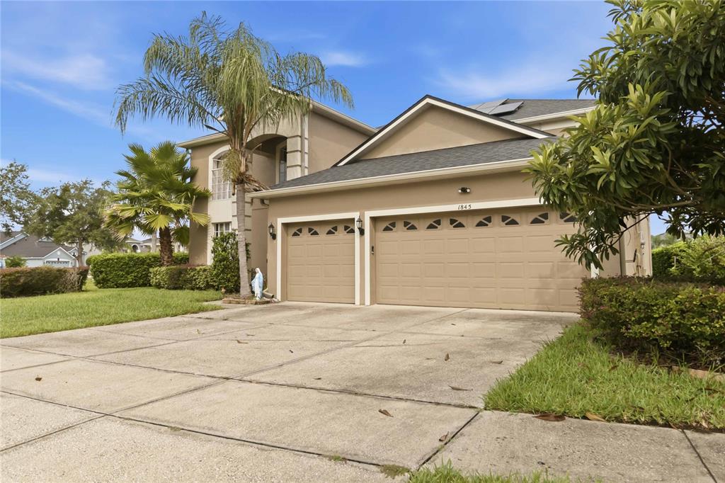 A two-story house with a beige exterior, a three-car garage, and a palm tree — 1845 OAK GROVE CHASE DRIVE, ORLANDO, FL