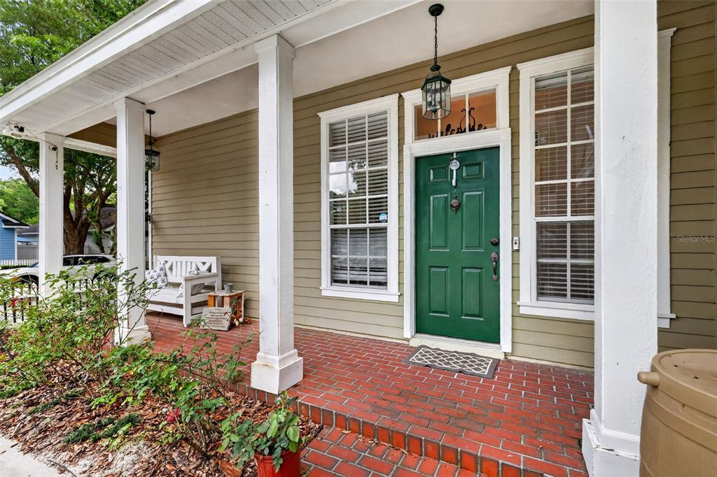 A front porch with a green door, brick flooring, and white columns — 5108 SW 103RD WAY, GAINESVILLE, FL