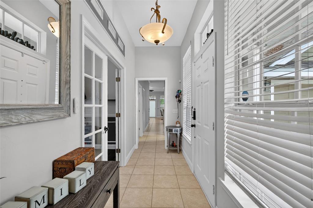 A bright entryway features tile flooring, a glass-paneled door, and a hallway leading further inside — 5108 SW 103RD WAY, GAINESVILLE, FL