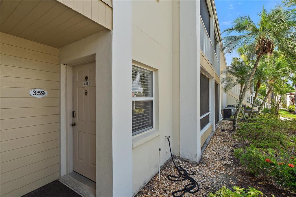 The exterior of a multi-story apartment building features a tan door labeled 359 and landscaping — 425 CERROMAR TERRACE UNIT 359, VENICE, FL