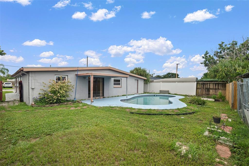 A backyard view of a single-story house with a swimming pool and a covered patio — 4712 BESSIE ROAD, TAMPA, FL