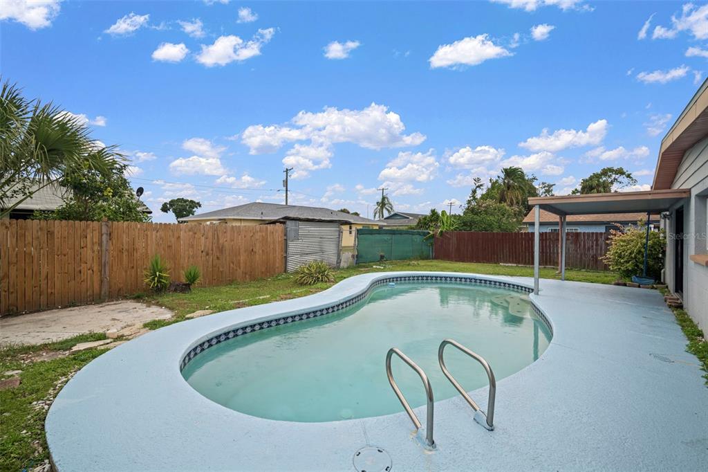 A backyard features a kidney-shaped swimming pool, a concrete patio, and a wooden privacy fence — 4712 BESSIE ROAD, TAMPA, FL