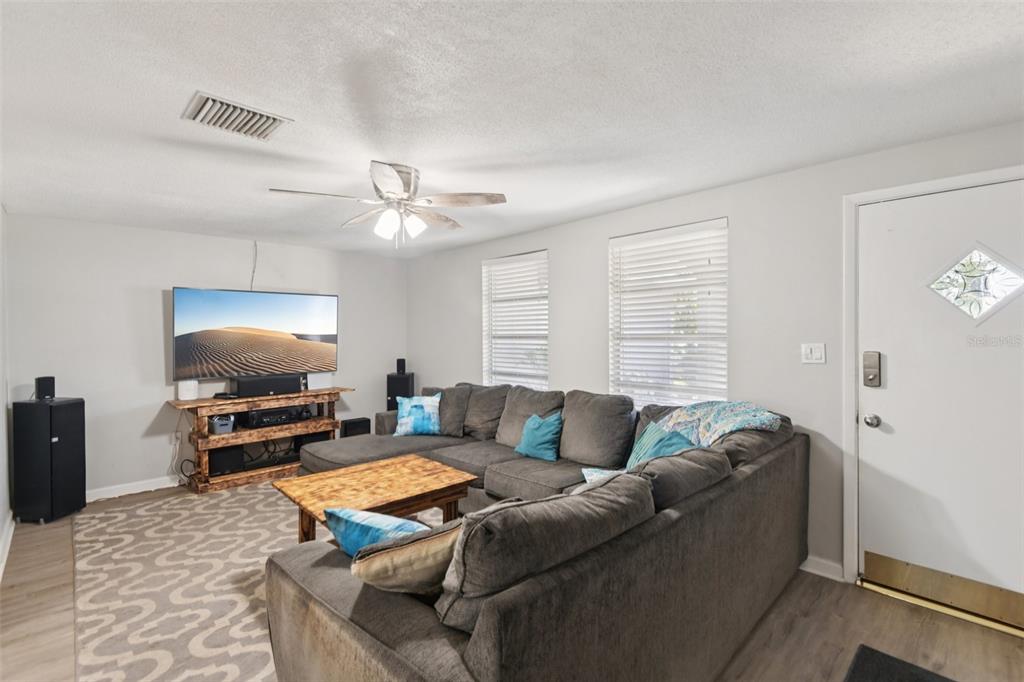 A living room features a gray sectional sofa, a wooden coffee table, and a television console — 7102 CHERRY LAUREL DRIVE, PORT RICHEY, FL
