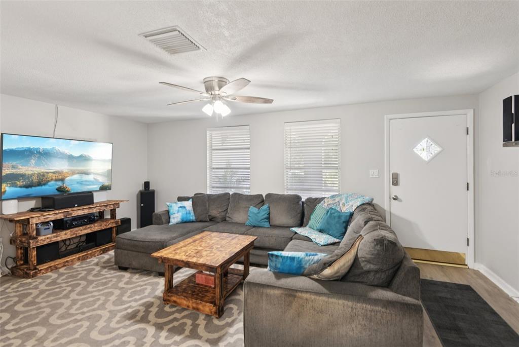 A living room features a grey sectional sofa, a wooden coffee table, and a television console — 7102 CHERRY LAUREL DRIVE, PORT RICHEY, FL