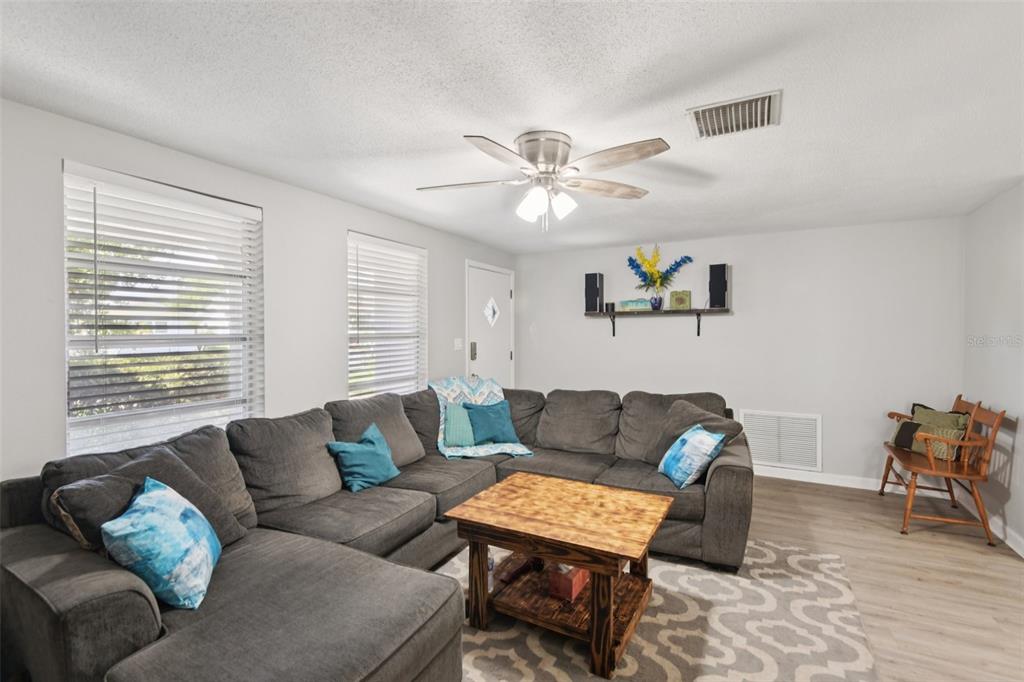 A living room features a large gray sectional sofa, a wooden coffee table, and light flooring — 7102 CHERRY LAUREL DRIVE, PORT RICHEY, FL