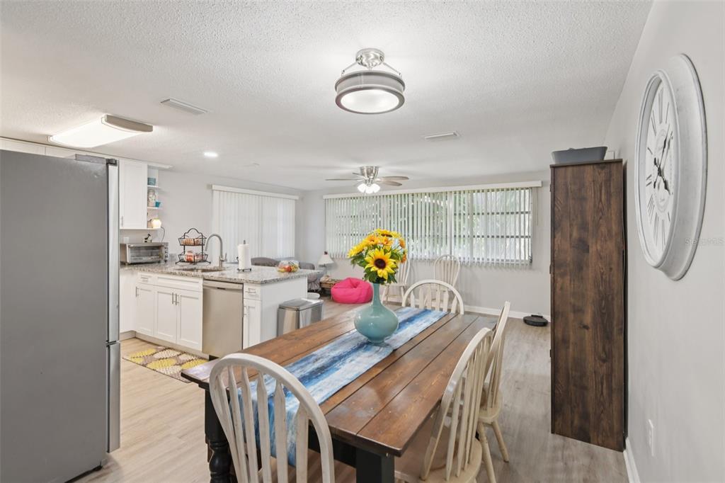 A dining area with a wooden table and chairs opens into a white kitchen — 7102 CHERRY LAUREL DRIVE, PORT RICHEY, FL