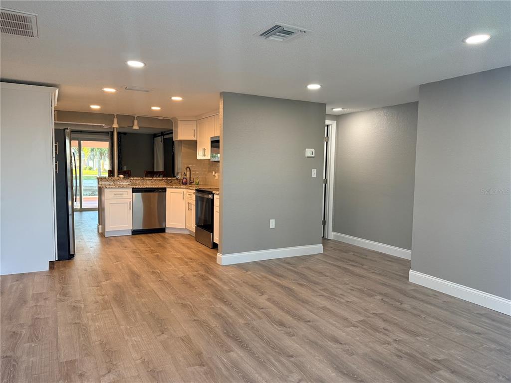 A kitchen with white cabinets and stainless steel appliances opens into a living area — 6623 BOATYARD DRIVE, HUDSON, FL