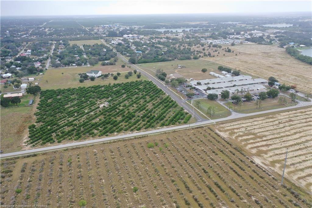 An aerial view shows a large agricultural field, a commercial building, and surrounding rural landscape — 525 E WINTHROP STREET, AVON PARK, FL