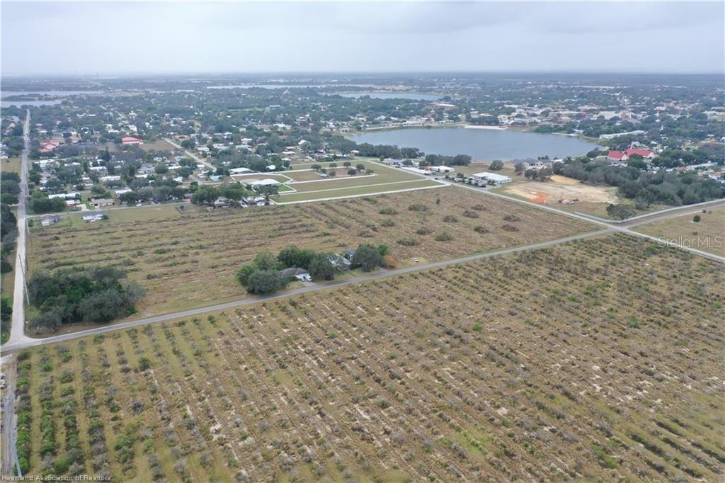 An aerial view shows a large, undeveloped field with a house and nearby lake — 525 E WINTHROP STREET, AVON PARK, FL