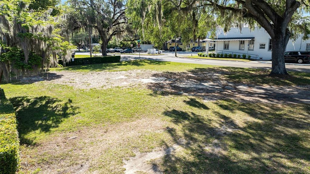 A vacant, grassy lot with mature trees and Spanish moss sits near a paved street — 0 SW 2ND AVENUE, OCALA, FL