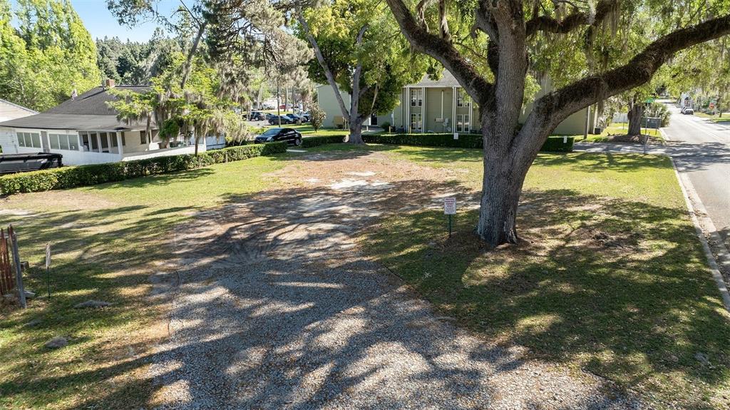 An elevated view of a vacant, grassy lot with a large tree and gravel driveway — 0 SW 2ND AVENUE, OCALA, FL