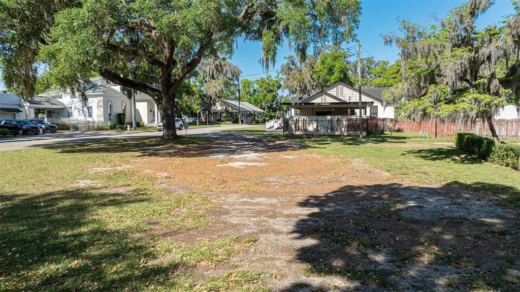 A vacant, grassy lot with scattered trees and nearby houses under a clear blue sky — 0 SW 2ND AVENUE, OCALA, FL