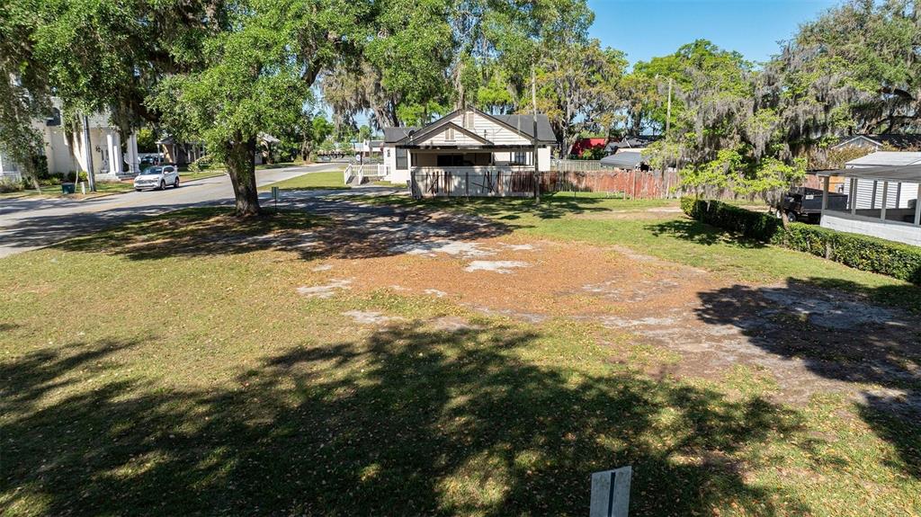 An elevated view of a vacant, grassy residential lot with scattered trees and a neighboring house — 0 SW 2ND AVENUE, OCALA, FL