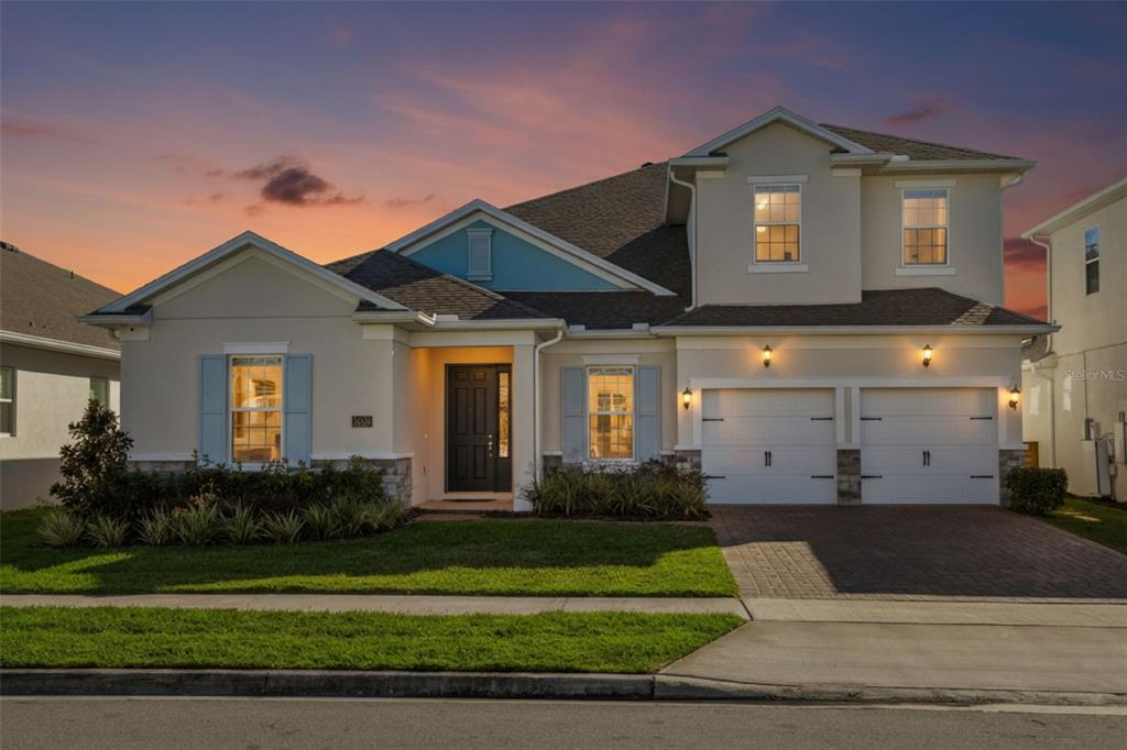 A two-story suburban house with a beige stucco exterior, blue shutters, and a two-car garage — 19334 BANFIELD PLACE, ORLANDO, FL