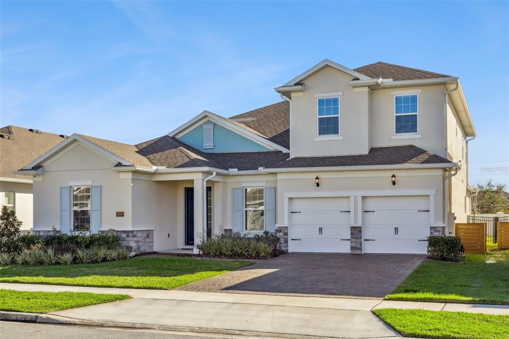 A two-story suburban house with a two-car garage, light stucco siding, and a paved driveway — 19334 BANFIELD PLACE, ORLANDO, FL