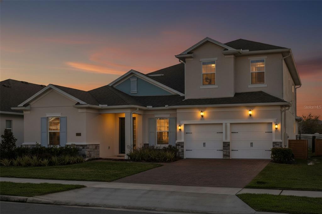 A two-story suburban house with a two-car garage and light-colored stucco exterior at dusk — 19334 BANFIELD PLACE, ORLANDO, FL