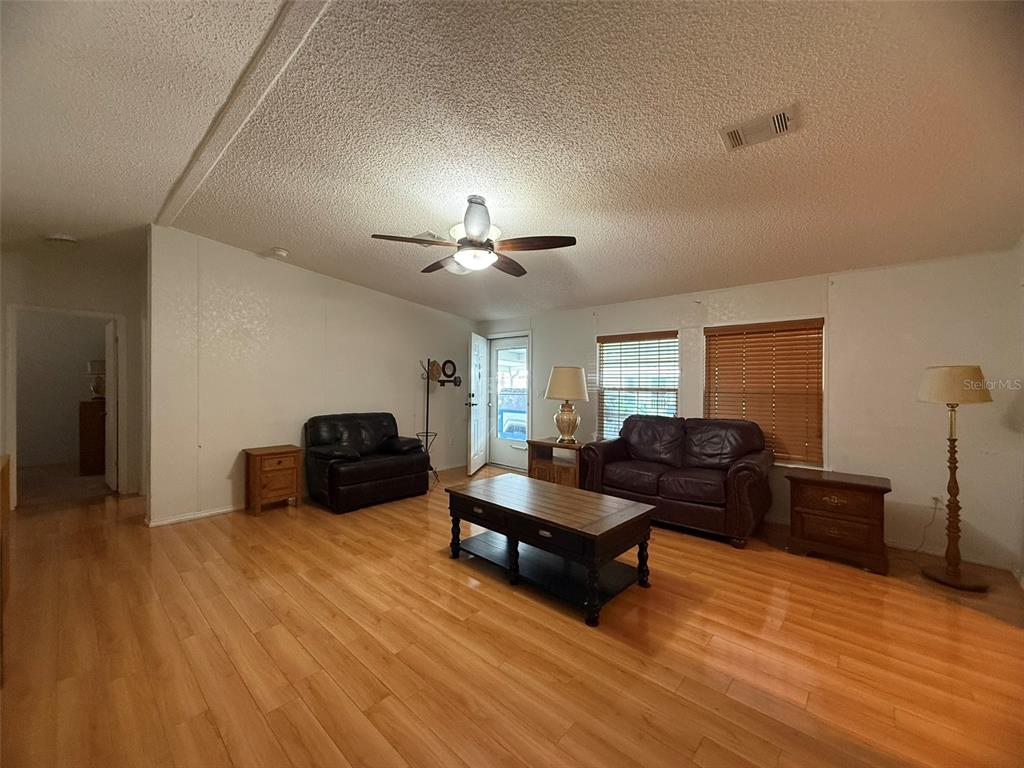 A living room features wood-look flooring, a ceiling fan, and two dark leather sofas — 5320 LAUREL OAK DRIVE, WINTER HAVEN, FL