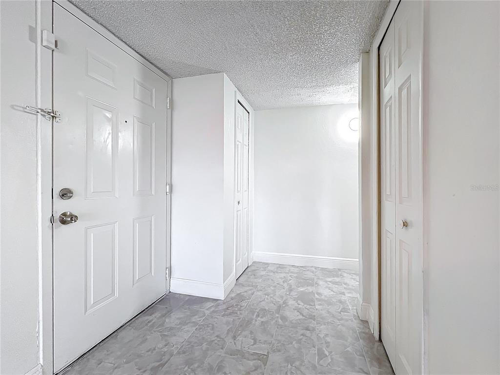 An entryway with white walls, a textured ceiling, gray tile flooring, and two closet doors — 802 SKY LAKE CIRCLE UNIT C, ORLANDO, FL