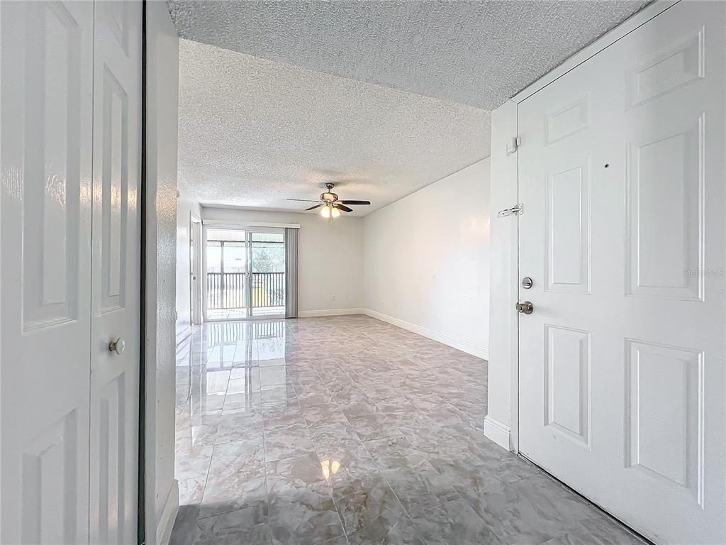 An entryway leads into a living room with tiled floors, a ceiling fan, and sliding doors — 802 SKY LAKE CIRCLE UNIT C, ORLANDO, FL