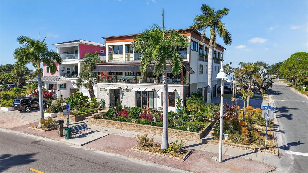 A multi-story building with a balcony and palm trees sits next to a paved street — 5659 SHORE BOULEVARD S, GULFPORT, FL