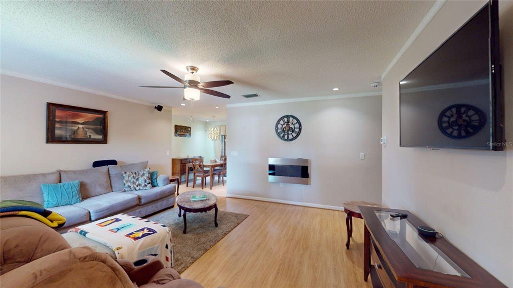 A living room features a sectional sofa, a wall-mounted television, and a fireplace — 6960 PINECREST LANE N, PINELLAS PARK, FL