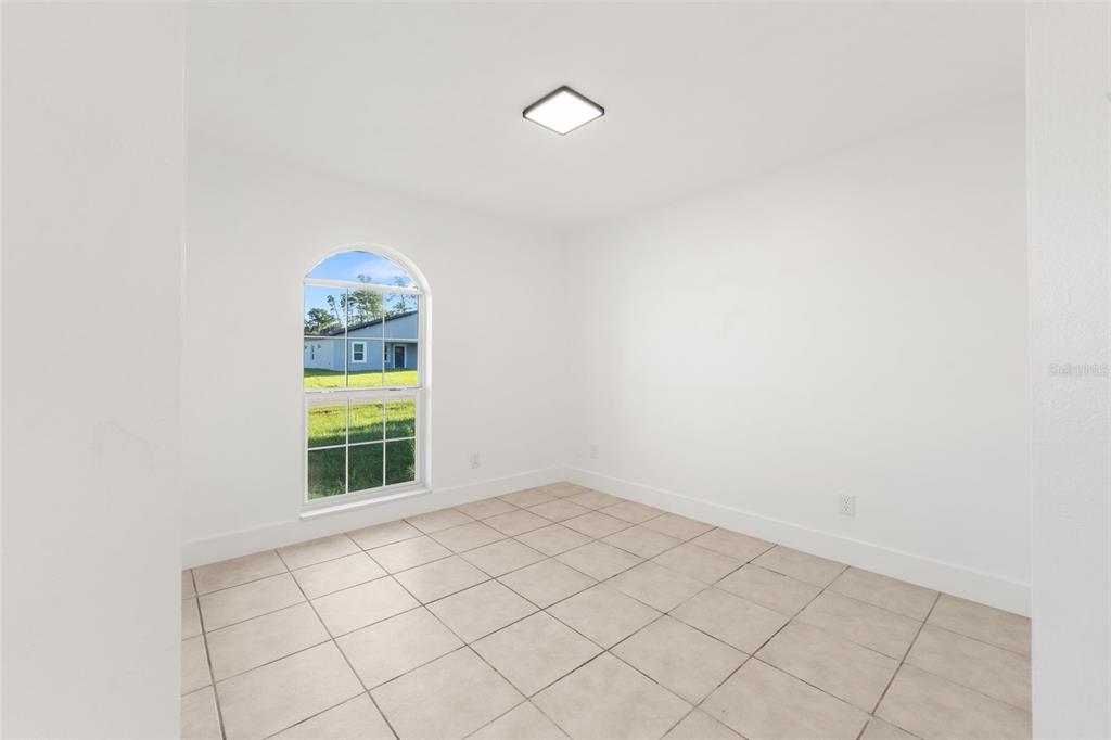 An empty room with white walls, tiled flooring, and an arched window — 3988 SW 169TH LN, OCALA, FL