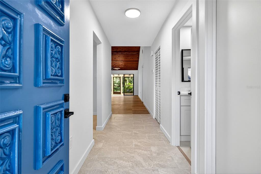 A view from a blue front door into a hallway with tile flooring — 7607 4TH AVENUE W, BRADENTON, FL
