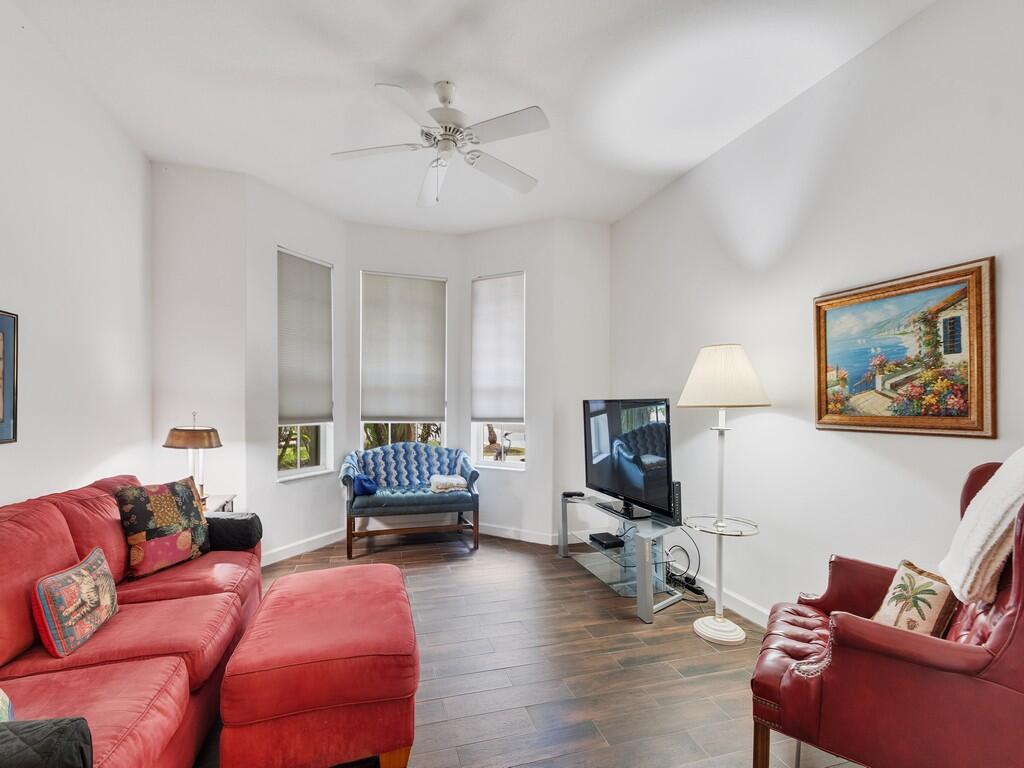 A living room features a red sofa, a red armchair, a television, and a ceiling fan — 3830 Nags Head Place SW, Vero Beach FL 32968, VERO BEACH, FL
