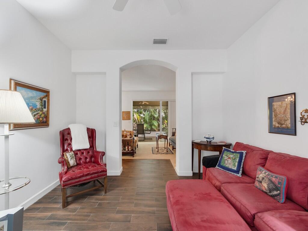 A living room features a red leather armchair, a red sofa, and tiled flooring — 3830 Nags Head Place SW, Vero Beach FL 32968, VERO BEACH, FL