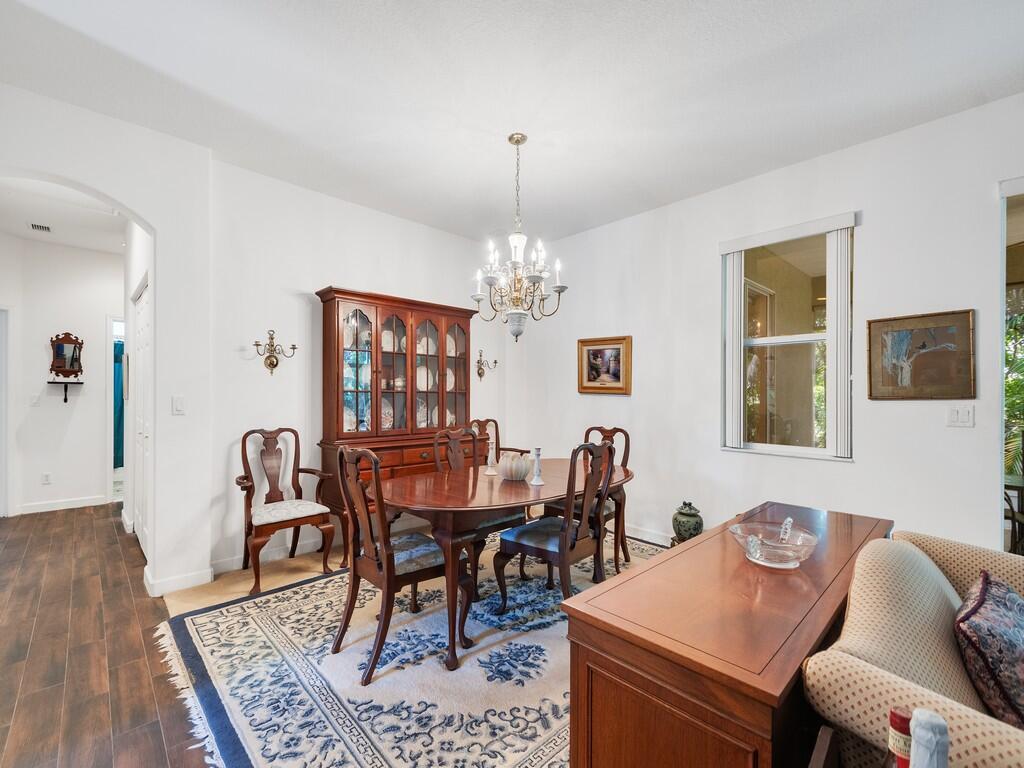 A dining room features a wooden table, a hutch, a chandelier, and a patterned rug — 3830 Nags Head Place SW, Vero Beach FL 32968, VERO BEACH, FL