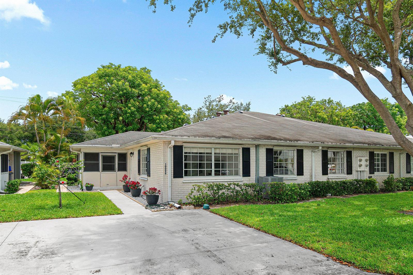 A single-story brick duplex with a screened-in porch, black shutters, and a concrete driveway — 10098 S 40th Drive S, Boynton Beach FL 33436, BOYNTON BEACH, FL
