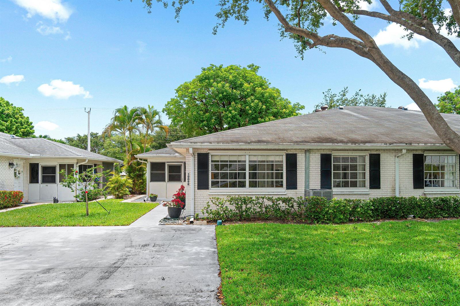 A single-story white brick duplex with black shutters and a concrete driveway under a tree — 10098 S 40th Drive S, Boynton Beach FL 33436, BOYNTON BEACH, FL
